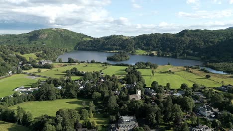 Aerial-video-footage-Grasmere-Lake-and-Village,-Town-in-the-Cumbrian-Lake-District-National-Park-England-UK-on-a-beautiful-sunny-day