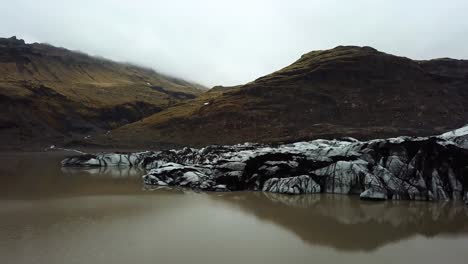 Vista-Aérea-Del-Glaciar-Sólheimajökull,-Derritiéndose-En-Agua-Oscura,-En-Verano,-Islandia