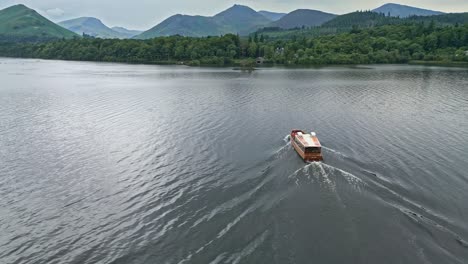 Drone-Aerial-footage-of-a-loan-boat-on-Derwentwater,-Keswick,-a-calm-lake-with-river-boats-and-a-stormy-sky