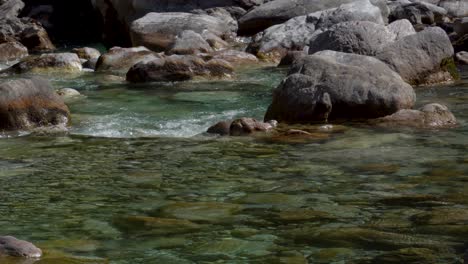Stones-of-riverbed-washed-by-crystal-water-of-mountain-river-streaming-from-melted-snow