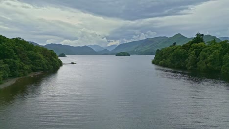 Drone-Aerial-video-footage-of-Derwentwater,-Keswick,-a-calm-lake-with-river-boats-and-a-stormy-sky