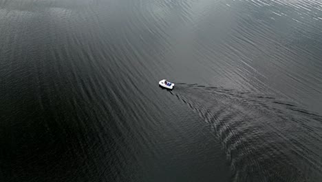Drohnen-Luftaufnahmen-Eines-Kleinen-Bootes-Auf-Derwentwater,-Keswick,-Einem-Ruhigen-See-Mit-Flussbooten-Und-Einem-Stürmischen-Himmel