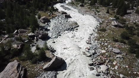 Drone-aerial-view-of-a-muddy-river-in-the-Swiss-alps,-Rocky-Mountain-valley,-strong-current-and-waves