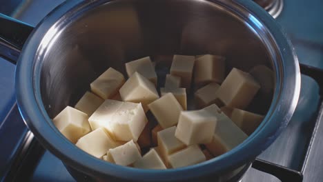 Putting-Cubed-Cheese-And-Milk-Into-Stainless-Pot