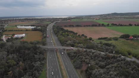 Aerial-Drone-Orbit-Showing-Of-Busy-Hungarian-Highway,-Beautiful-Lake-In-The-Background