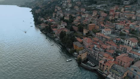 Aerial-tilt-over-lake-como-village-side-showing-mediterranean-houses-architecture-with-alp-mountains-in-the-background---moody-cinematic