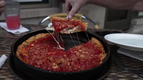 Chicago-style-pizza-at-Lou-Malnati's-Pizzeria-in-Evanston,-Illinois-with-man-serving-pizza
