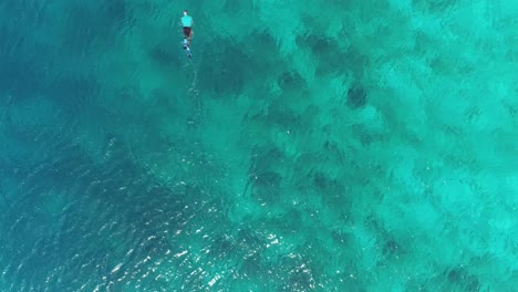 Man-snorkeling-alone-birds-view-swimming-out-of-frame-clear-waters