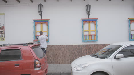 Footage-of-a-man-across-the-street-painting-the-edges-of-a-window-in-Colombia