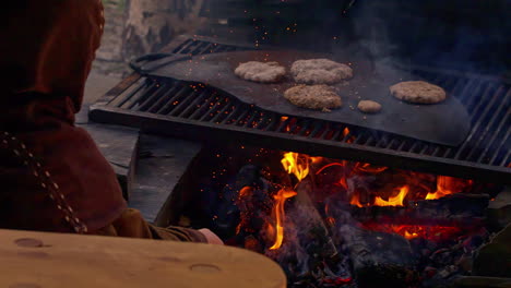 Beef-patties-or-sausages-grilling-on-a-wood-burning-outdoor-stove