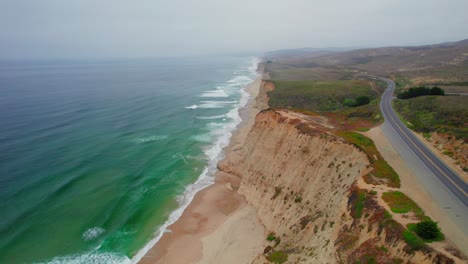 Aerial-view-drone-shot-rotation-of-California-coast-rock-cliffs-on-a-foggy-day-on-Pacific-Coast-Highway-at-San-Gregorio-State-Beach
