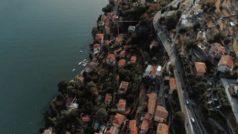 Aerial-Bird-view-tilt-over-lake-come-and-houses-cars-roads-of-Torriggia---moody-cinematic