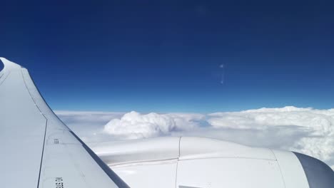 Window-seat-view-onto-the-plane's-wing-and-engine-above-thick-white-clouds