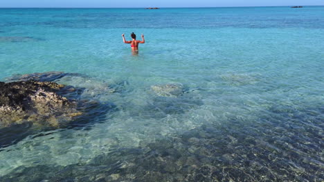 Young-enthusiastic-girl-takes-advantage-of-being-alone-in-the-turquoise-waters-of-Elafonisi-beach-to-dance