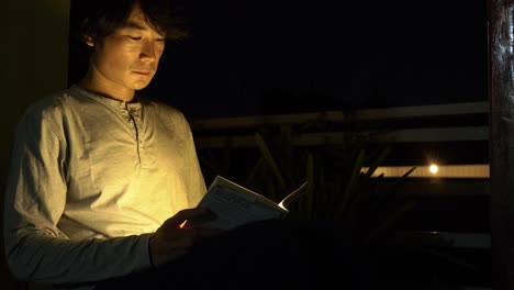 Side-On-Shot-Of-A-Smart-Man-Reading-A-Book-Lit-By-A-Small-Light-At-Night-Before-Bed