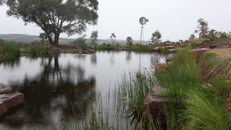 Ein-Mann-Schwimmt-In-Seinem-Farmdamm-In-Kaltem-Wasser,-Während-Es-In-Australien-Regnet