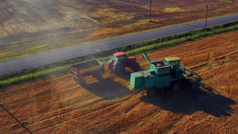 Combine-Harvester-And-Tractor-At-Work-Harvesting-Wheat---aerial-shot