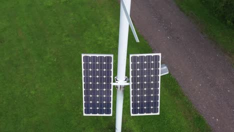 Solar-panels-and-small-wind-turbine-powering-street-light-on-pole,-aerial-view
