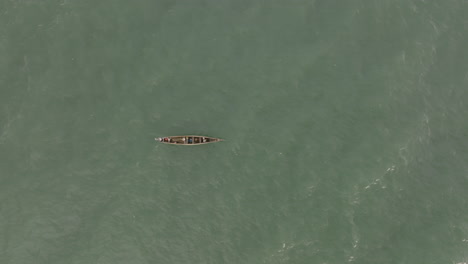 Static-top-down-aerial-footage-of-a-small-fishing-boat-rocking-the-waves-of-the-ocean-off-the-coast-of-Sierra-Leone
