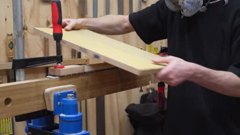 Male-guitar-luthier-sanding-guitar's-neck-smooth,-rounding-the-wood-surface