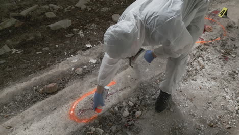 Forensic-scientist-paints-an-orange-spray-mark-around