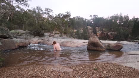An-Australian-man-lies-down-in-a-freezing-cold-mountain-pool-near-a-waterfall-in-the-middle-of-winter-in-the-Australian-bush