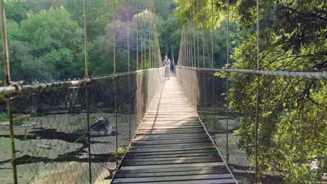 Male-tourist-walks-on-Suspension-rope-bridge-in-the-forest-and-taking-photos-at-scenery
