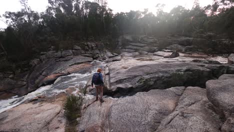 A-man-hiking-over-a-waterfall-near-a-rocky-gorge-in-the-Australian-bush