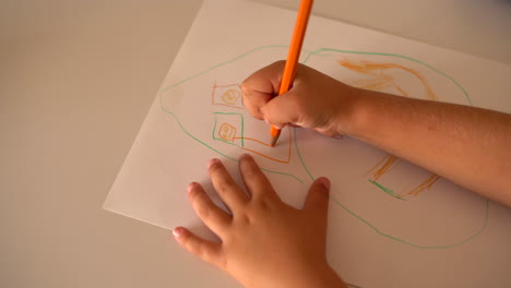 A-child-drawing-on-paper-with-coloured-pencils