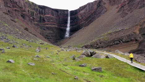 Mujer-Caminando-Hacia-Una-Cascada-En-Islandia
