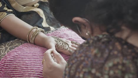 Artist-Applying-Mehndi-Tattoo-On-Brides-Hand-For