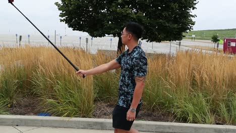 Man-walks-with-selfie-stick-in-park