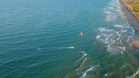 Luftaufnahme-Des-Kitesurfers,-Der-Während-Des-Sonnenuntergangs-Am-Mareny-Beach,-Valencia,-Spanien-über-Die-Wellen-Springt
