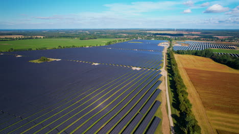 Aerial-push-back-flight-over-photovoltaic-farm-surrounded-by-colorful-agricultural-fields-in-nature