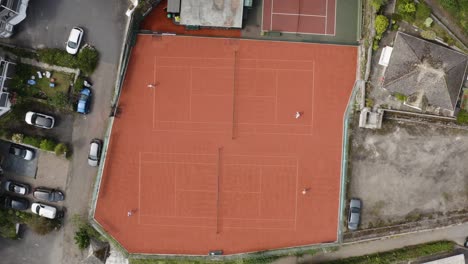 Rote-Tennisplätze-Mit-Zwei-Athletischen-Spielern,-Die-Während-Eines-Spiels-Spielen