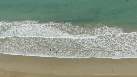 Overhead-View-Of-Two-Surfers-Going-To-The-Sea-To-Surf-At-Fistral-Beach-In-Newquay,-Cornwall,-UK