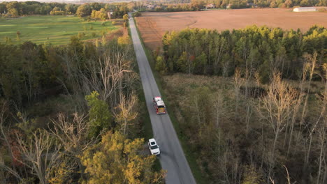 Aerial-Tracking-View-of-Emergency-Fire-Truck-Vehicle-Driving-Fast-along-Countryside-Road-with-Flashing-Lights,-Rescue-First-Responder-Mission-for-Fire-Fighting-Alert,-Path-Route-Through-Nature-Lands