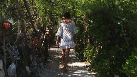 Woman-tourist-walks-down-path-on-small-island-for-lunch-in-farè-hut,-New-Caledonia