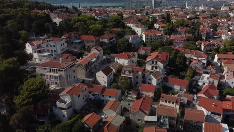 Aerial-tilting-shot-of-the-beautiful-traditional-rooftops-of-Split,-Croatia,-embraced-by-the-beautiful-Suma-Marjan-Park,-at-the-coastline-of-the-Adriatic-Sea