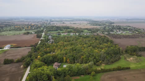 Aerial-Countryside-Landscape-in-Pelham-Ontario-Canada-in-Autumn-Season,-Rural-Neighborhood-Residential-Area-and-Road-along-the-Region,-Green-Fields-and-Agricultural-Lands-Around,-Skyline-Horizon