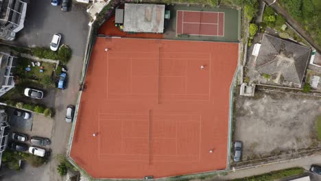 Roter-Tennisplatz-Von-Oben-Gesehen-Mit-Spielenden-Athleten