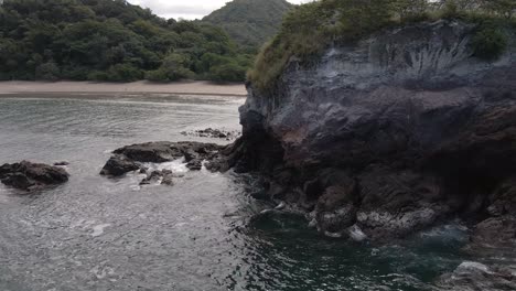 Slow-Rotation-Around-A-Large-Rock-Face-Revealing-A-Beautiful-Beach-And-Shoreline-At-Playa-Real-In-The-Guanacaste-Province