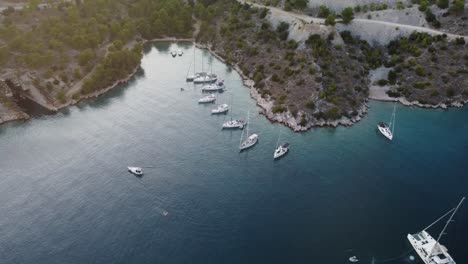 High-altitude-drone-orbit-view-of-a-wild-secluded-beach-at-the-coastline-of-Brac-Island,-Croatia,-Adriatic-Sea,-where-luxury-sailing-boats-are-anchored