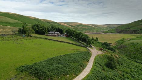 Drohnen-Luftaufnahmen-Von-Moorlandschaften-In-Den-Tälern-Von-Yorkshire,-Die-Sich-Langsam-Einen-Fußweg-Hinauf-Zu-Einem-Bauernhaus-Bewegen