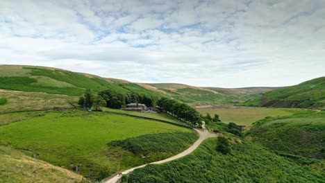 Aerial-footage-of-Yorkshire-countryside-valleys-moorland-and-moving-slowly-up-a-footpath-towards-a-farmhouse
