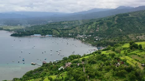 Natural-green-mountain-landscape-on-Lombok-Island-with-boats-anchored-in-Mentigi-Bay,-aerial