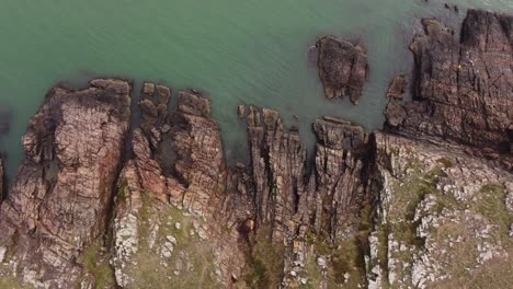 Aerial-top-down-shot-of-rocky-coastline-and-cliffs-in-front-of-Atlantic-Ocean-in-Uruguay