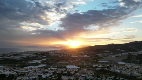 Beautiful-sunset-shot-from-drone-rising-up-over-Spanish-countryside-with-clouds-over-sea