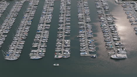 Aerial-footage-slowly-panning-up-and-moving-backwards-showing-a-large-harbor-full-of-speed-boats-in-the-morning-sun