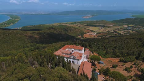 Iconic-cinematic-Monte-Argentario-monastery-lagoon,-facing-the-ancient-old-town-Orbetello-close-to-the-Maremma-nature-park-in-Tuscany,-Italy-near-Grosseto-in-summer-with-blue-sky